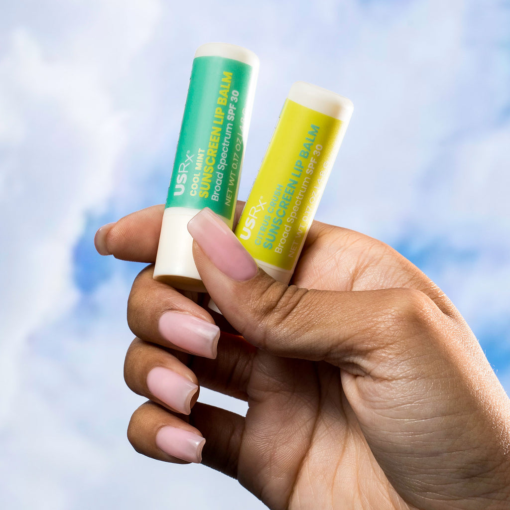 Woman holding 2 USRX Sunscreen Lip Balms in her hand