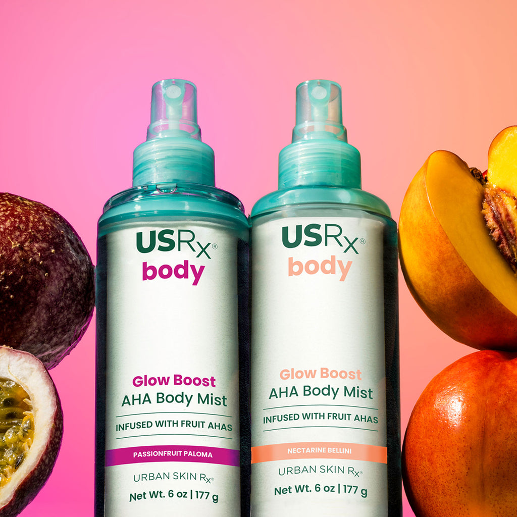 Bottles of USRX Glow Boost AHA Body Mists in Passionfruit Paloma and Nectarine Bellini surrounded by tropical frutis
