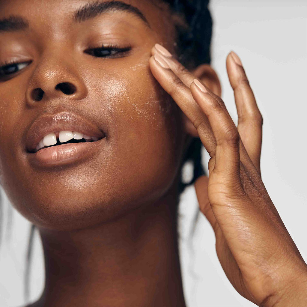 African American model exfoliating her face with Lacticglow Micropolish Gentle Cleansing Gel