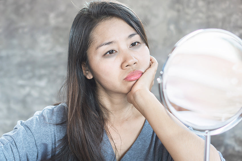 woman examining dark undereye circles